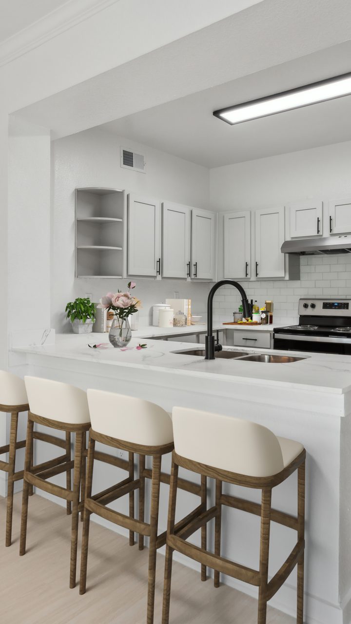 a white kitchen with stainless steel appliances and bar stools at The Stetson