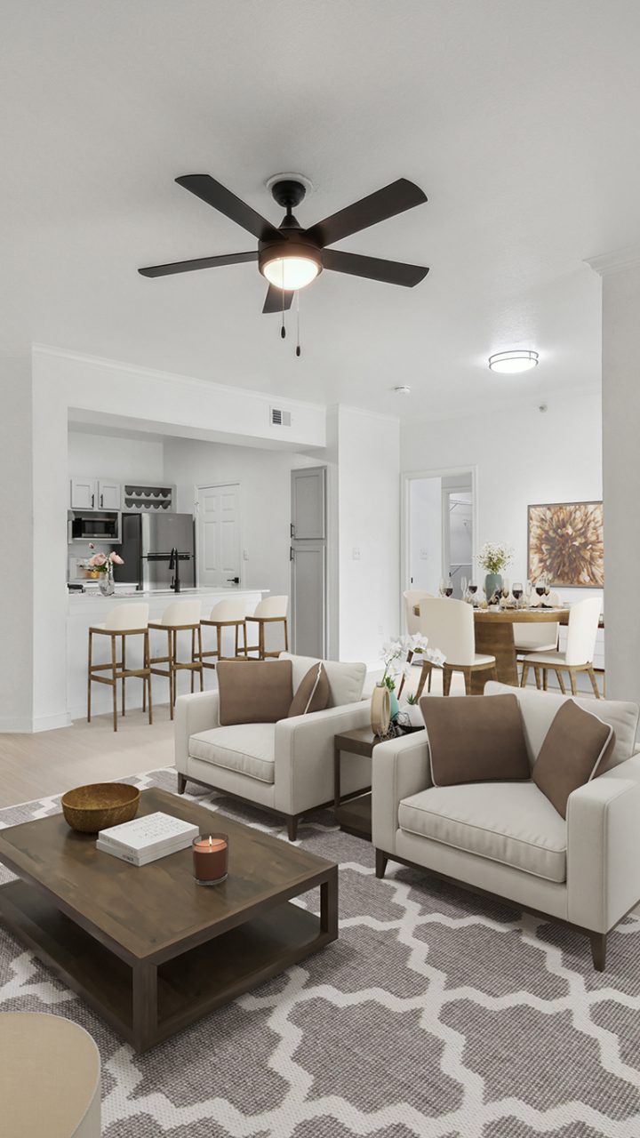 a living room with a ceiling fan and white walls at The Stetson
